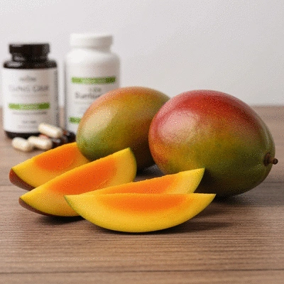 Close-up of African mango slices and whole fruit on a wooden table with nutritional supplements in the background